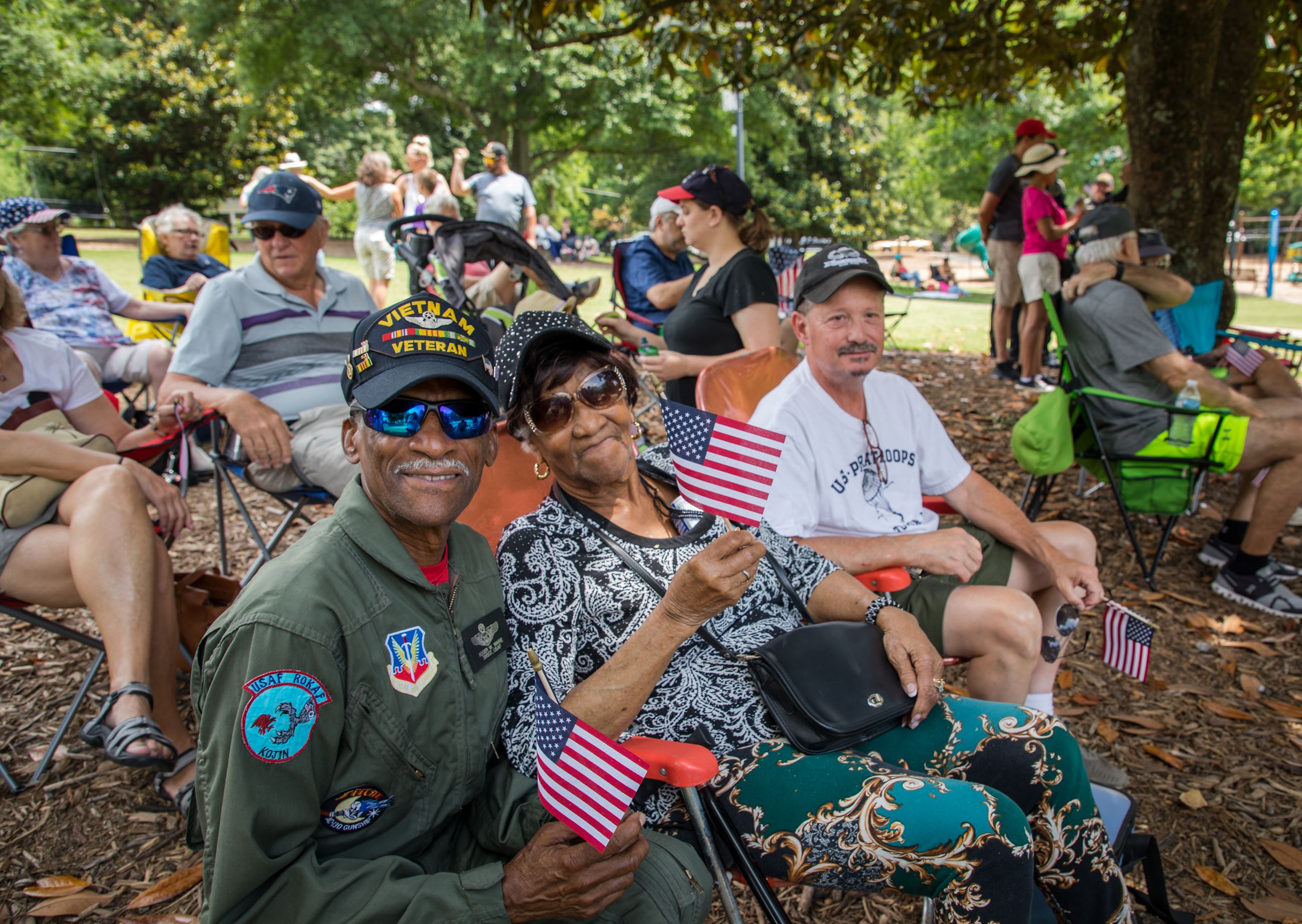 veterans sit and wave american flag at memorial day event in park