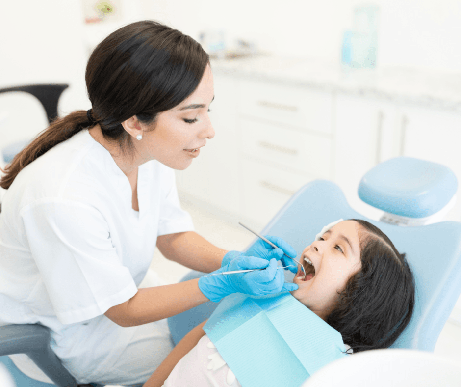 Women dentist examining little girls teeth